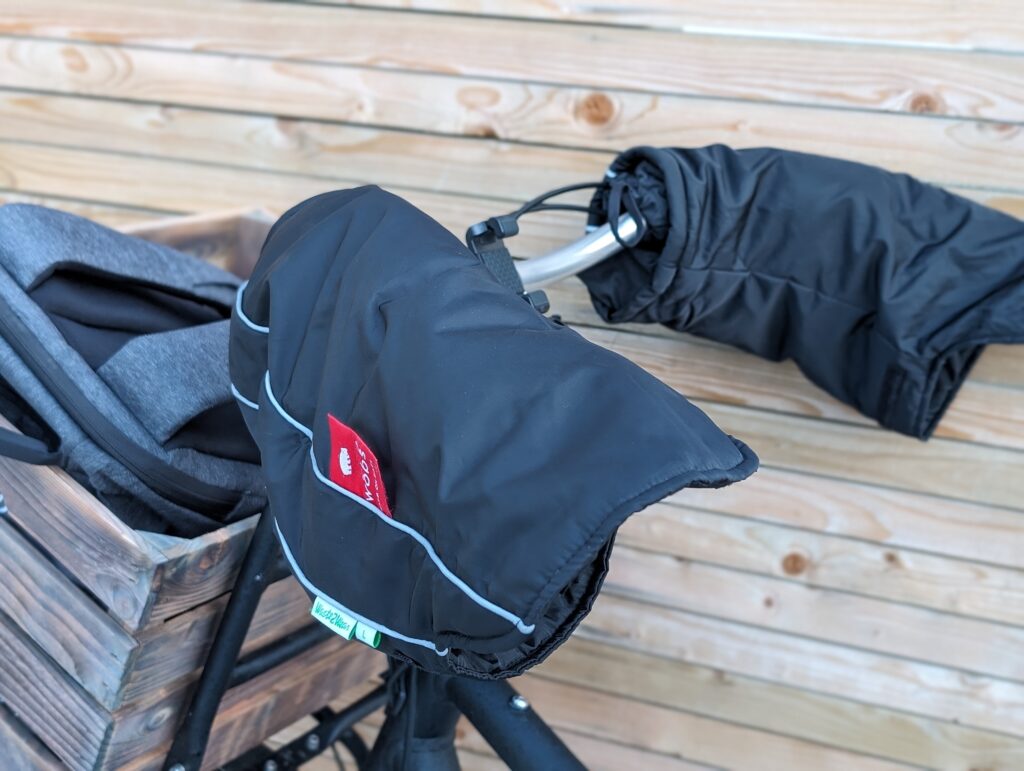 Bar mitts fitted on a bicycle's handlebars, and also a wooden crate fitted to the front of the bike.