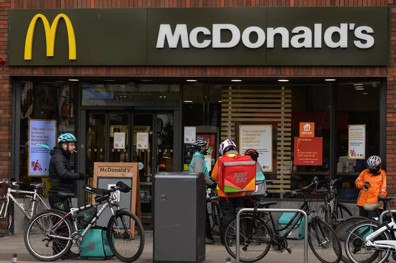 A number of bicycle food delivery riders outside of a Macdonalds restaurant